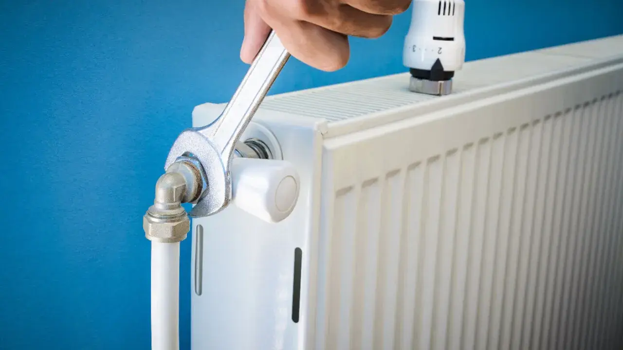Main tenant resserre une connexion sur un radiateur qui fait du bruit.