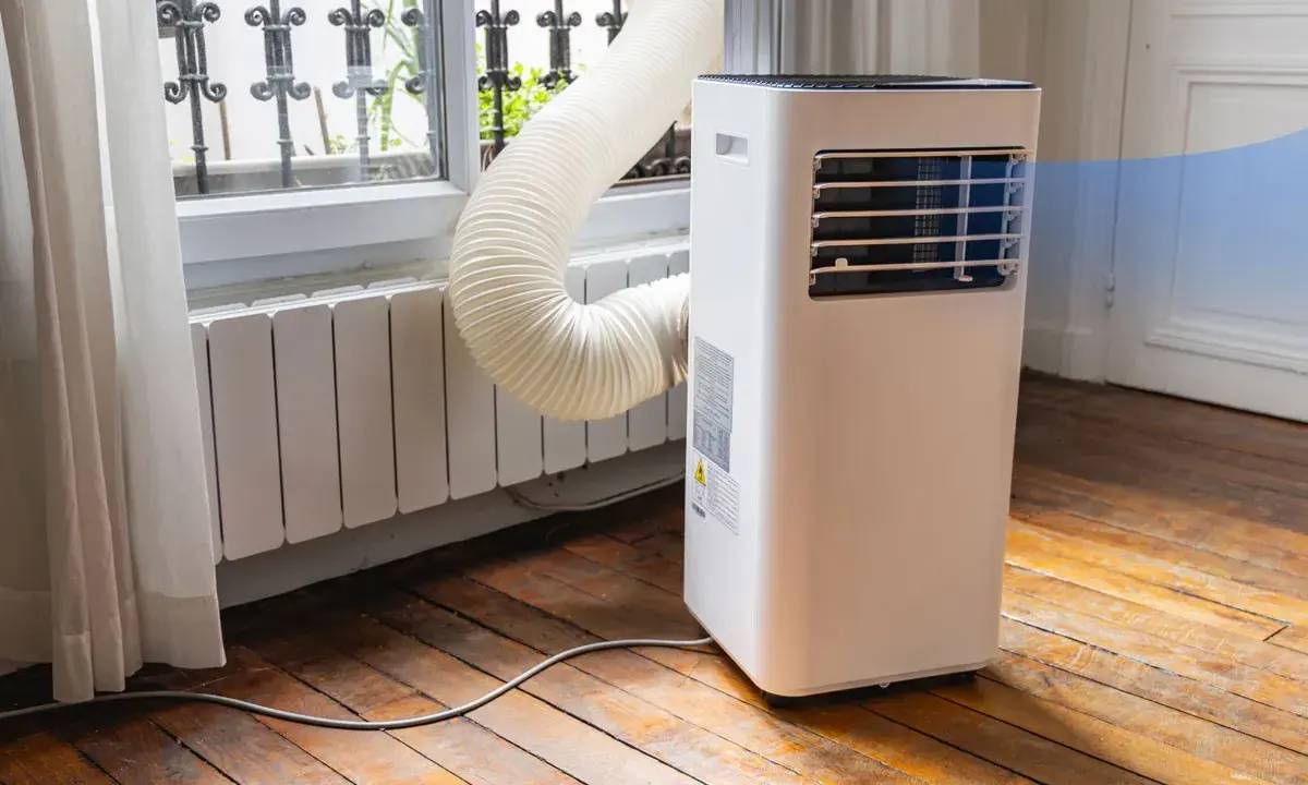 Climatiseur monobloc avec son tuyau d'évacuation vers la fenêtre. Un inconvénient : le tuyau peut être encombrant.