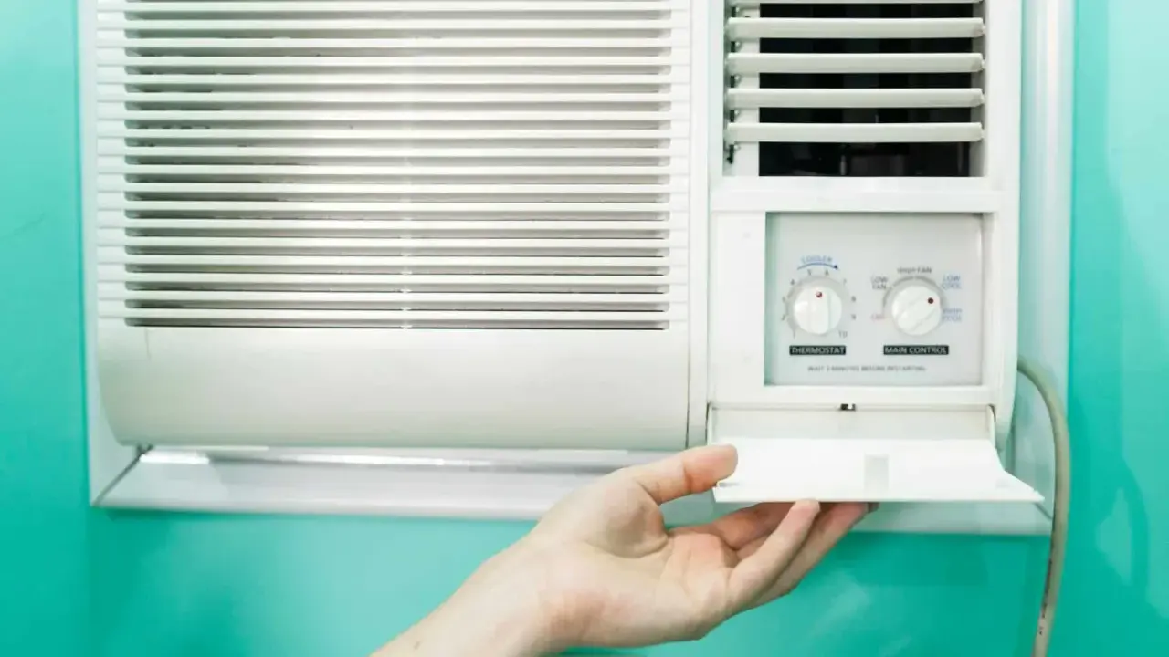 Clim 3.5 kW : combien de m2 peut-il refroidir ? Une main ouvre le compartiment d'un climatiseur mural blanc.