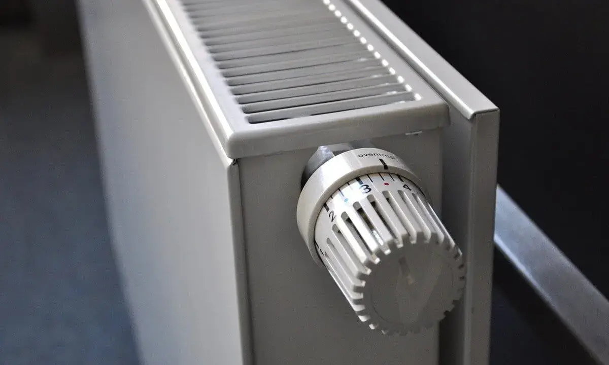 Gros plan sur un radiateur blanc, élément clé d'une installation chauffage central, avec sa molette de réglage de température.