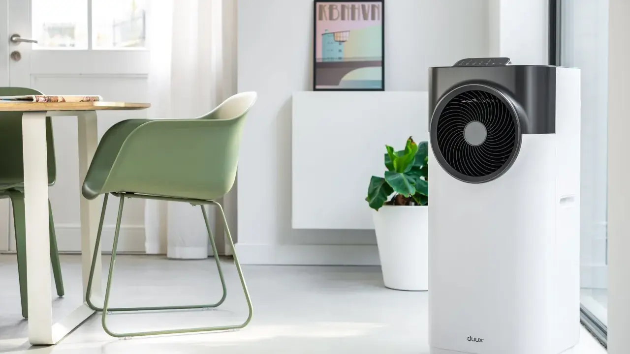 Le climatiseur pure blizzard, blanc et gris, trône dans un salon moderne aux côtés d'une plante verte et d'un tableau.
