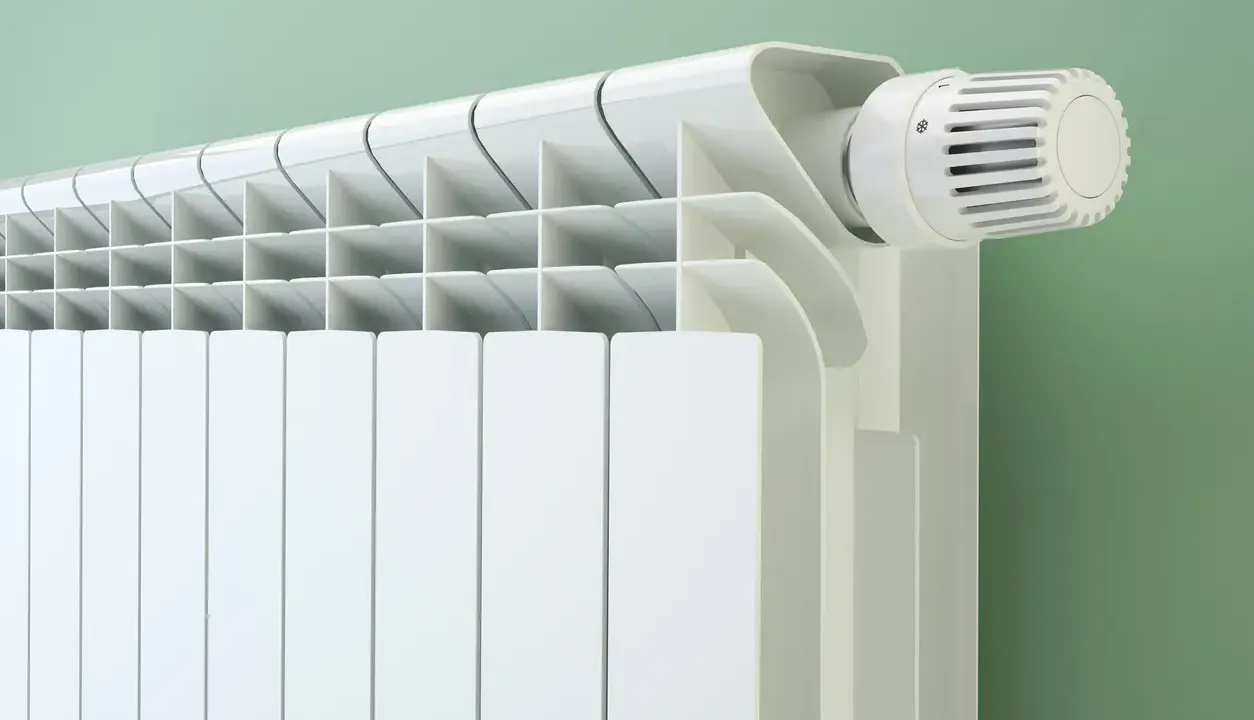 Radiateur blanc moderne avec thermostat. Le fluide caloporteur circule pour chauffer la pièce.