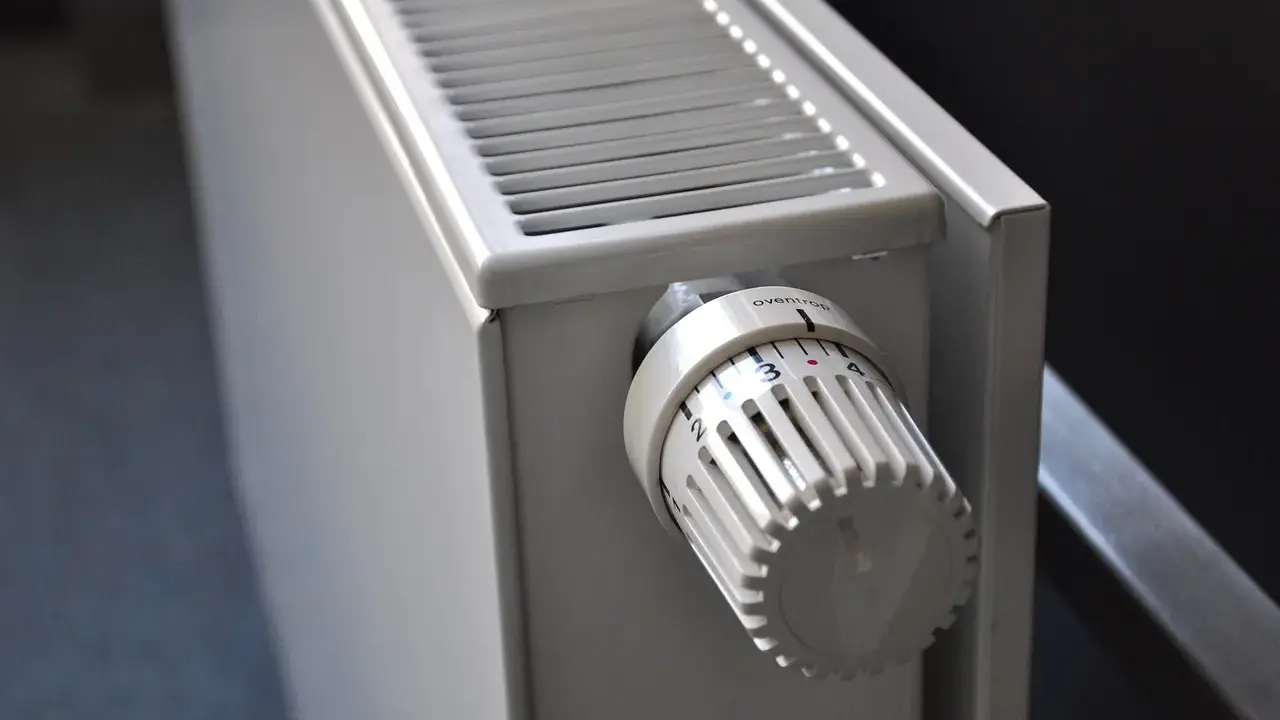 Gros plan sur un radiateur blanc, avec son thermostat réglable. Ce radiateur fonte ou céramique est prêt à chauffer votre intérieur.