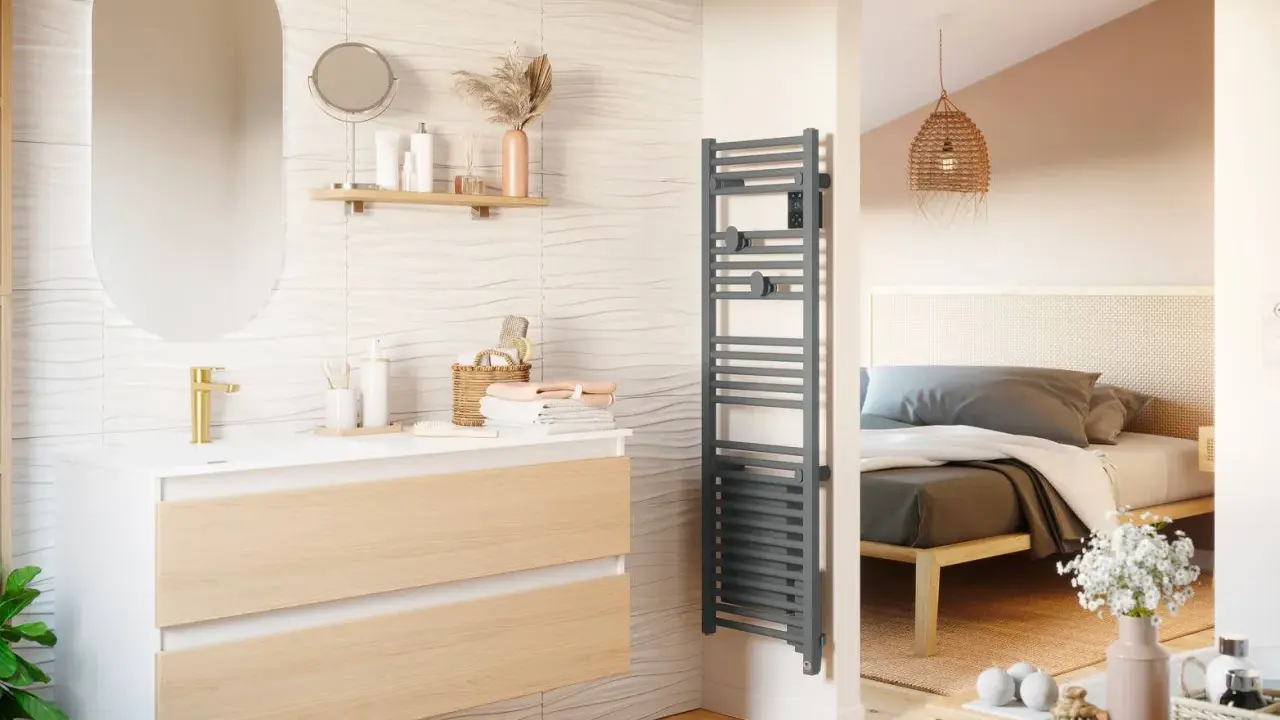 Salle de bain moderne avec meuble vasque, miroir ovale et sèche-serviettes gris. La puissance du sèche serviette assure des serviettes chaudes.