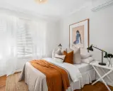 Une chambre confortable avec un lit douillet, des rideaux blancs et une unité de climatisation discrètement placée en hauteur, idéale pour savoir ou placer une clim dans une chambre.