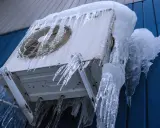 Unité intérieure clim qui givre, recouverte de stalactites de glace impressionnantes. L'appareil semble figé par le froid intense.