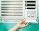 Clim 3.5 kW : combien de m2 peut-il refroidir ? Une main ouvre le compartiment d'un climatiseur mural blanc.