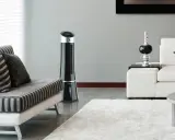 Ventilateur tour noir, solution pour la consommation clim mobile. Un salon moderne avec canapé et tapis blanc.