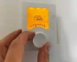 Main tenant ajuste la hauteur du thermostat pour optimiser le confort. L'écran affiche 19.0°C.