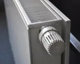 Gros plan sur un radiateur blanc, élément clé d'une installation chauffage central, avec sa molette de réglage de température.
