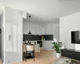 Un studio moderne avec cuisine, coin repas et salon. Un climatiseur discret est installé au plafond, assurant le confort.