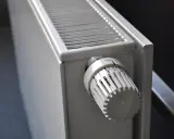 Gros plan sur un radiateur blanc, avec son thermostat réglable. Ce radiateur fonte ou céramique est prêt à chauffer votre intérieur.