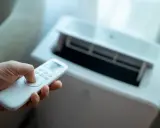 Main tenant utilise la télécommande pour régler son meilleur climatiseur mobile pas cher.