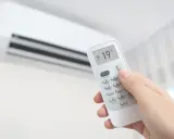 Main tenant ajuste la climatisation chaud à 19°C avec une télécommande.