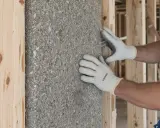 Pose d'isolant en laine de roche dans une structure en bois. Les avantages et inconvénients de ce matériau sont à considérer pour une isolation efficace.