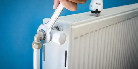 Main tenant resserre une connexion sur un radiateur qui fait du bruit.