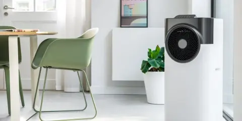 Le climatiseur pure blizzard, blanc et gris, trône dans un salon moderne aux côtés d'une plante verte et d'un tableau.