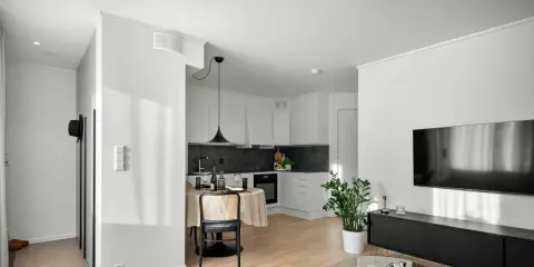 Un studio moderne avec cuisine, coin repas et salon. Un climatiseur discret est installé au plafond, assurant le confort.