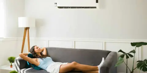 Une femme se détend sur un canapé sous un climatiseur, profitant de la puissance clim pour 40m2.
