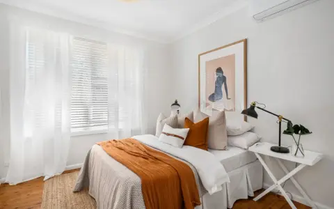 Une chambre confortable avec un lit douillet, des rideaux blancs et une unité de climatisation discrètement placée en hauteur, idéale pour savoir ou placer une clim dans une chambre.