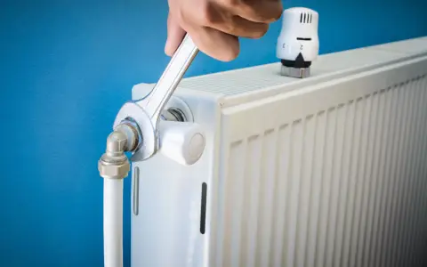 Main tenant resserre une connexion sur un radiateur qui fait du bruit.