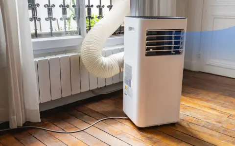Climatiseur monobloc avec son tuyau d'évacuation vers la fenêtre. Un inconvénient : le tuyau peut être encombrant.