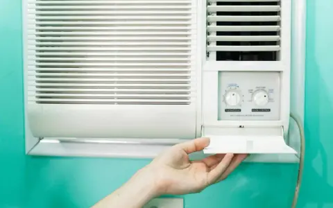 Clim 3.5 kW : combien de m2 peut-il refroidir ? Une main ouvre le compartiment d'un climatiseur mural blanc.