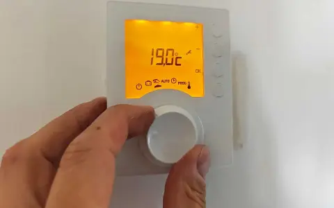 Main tenant ajuste la hauteur du thermostat pour optimiser le confort. L'écran affiche 19.0°C.