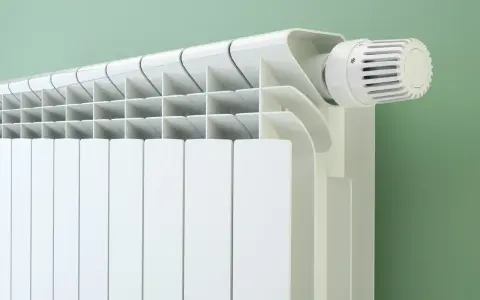 Radiateur blanc moderne avec thermostat. Le fluide caloporteur circule pour chauffer la pièce.