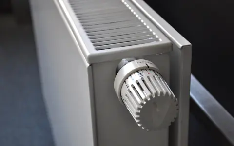 Gros plan sur un radiateur blanc, avec son thermostat réglable. Ce radiateur fonte ou céramique est prêt à chauffer votre intérieur.