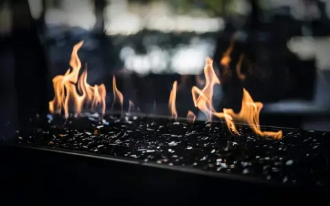 Flammes dansant sur des éclats de verre noir, évoquant le chauffage au pétrole, ses avantages et inconvénients.