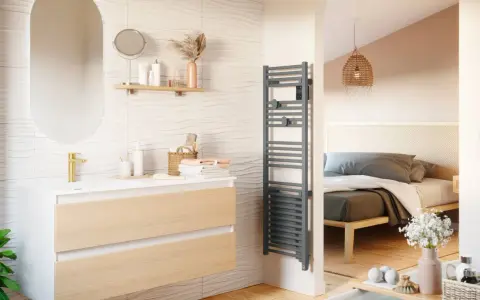 Salle de bain moderne avec meuble vasque, miroir ovale et sèche-serviettes gris. La puissance du sèche serviette assure des serviettes chaudes.