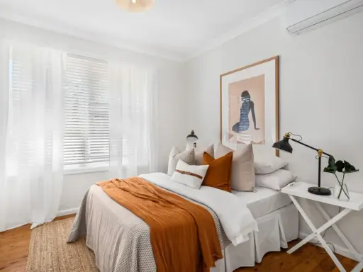 Une chambre confortable avec un lit douillet, des rideaux blancs et une unité de climatisation discrètement placée en hauteur, idéale pour savoir ou placer une clim dans une chambre.