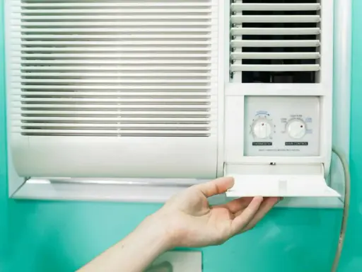 Clim 3.5 kW : combien de m2 peut-il refroidir ? Une main ouvre le compartiment d'un climatiseur mural blanc.