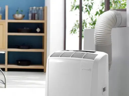 Climatiseur mobile blanc avec tuyau d'évacuation relié à une fenêtre.