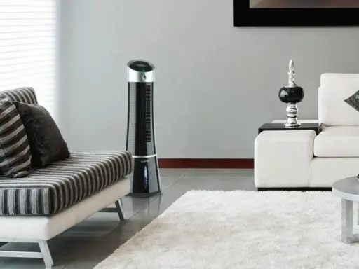 Ventilateur tour noir, solution pour la consommation clim mobile. Un salon moderne avec canapé et tapis blanc.
