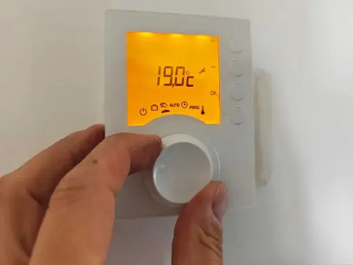 Main tenant ajuste la hauteur du thermostat pour optimiser le confort. L'écran affiche 19.0°C.