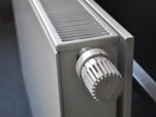 Gros plan sur un radiateur blanc, élément clé d'une installation chauffage central, avec sa molette de réglage de température.
