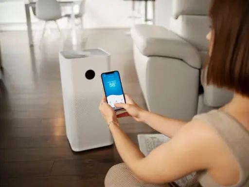 Une femme contrôle son climatiseur Proline via une application sur son smartphone, affichant 58% d'humidité intérieure.