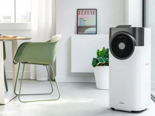 Le climatiseur pure blizzard, blanc et gris, trône dans un salon moderne aux côtés d'une plante verte et d'un tableau.