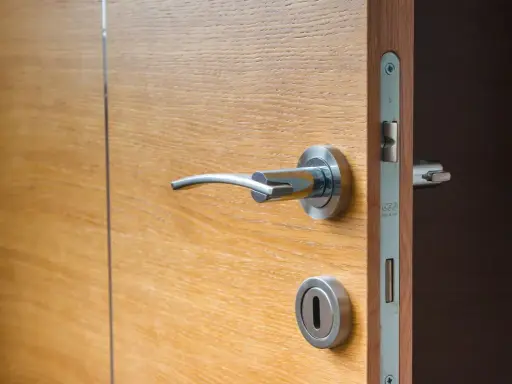 Porte isolante thermique entre garage et maison, en bois clair avec poignée chromée.