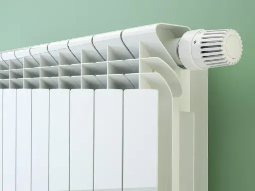 Radiateur blanc moderne avec thermostat. Le fluide caloporteur circule pour chauffer la pièce.