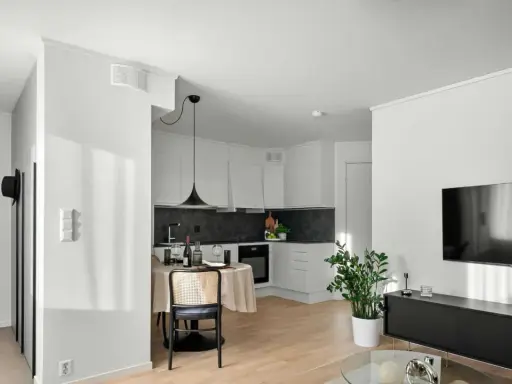 Un studio moderne avec cuisine, coin repas et salon. Un climatiseur discret est installé au plafond, assurant le confort.