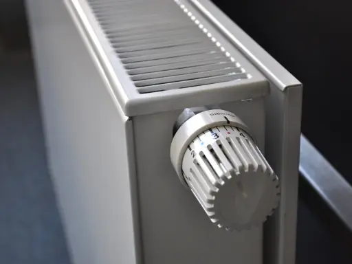 Gros plan sur un radiateur blanc, avec son thermostat réglable. Ce radiateur fonte ou céramique est prêt à chauffer votre intérieur.