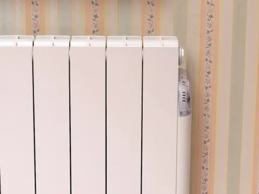 Un radiateur électrique à inertie blanc, avec son thermostat discret, se tient près d'un mur aux rayures pastel et fleuries.