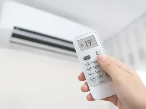 Main tenant ajuste la climatisation chaud à 19°C avec une télécommande.