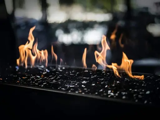 Flammes dansant sur des éclats de verre noir, évoquant le chauffage au pétrole, ses avantages et inconvénients.
