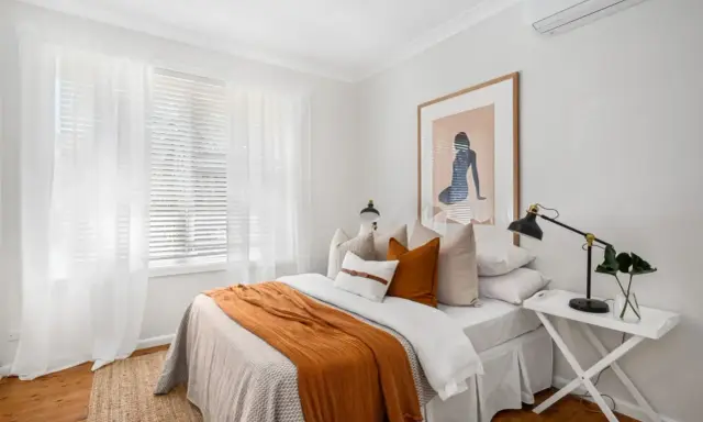 Une chambre confortable avec un lit douillet, des rideaux blancs et une unité de climatisation discrètement placée en hauteur, idéale pour savoir ou placer une clim dans une chambre.
