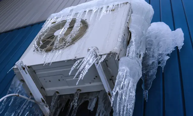 Unité intérieure clim qui givre, recouverte de stalactites de glace impressionnantes. L'appareil semble figé par le froid intense.
