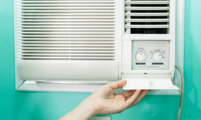 Clim 3.5 kW : combien de m2 peut-il refroidir ? Une main ouvre le compartiment d'un climatiseur mural blanc.
